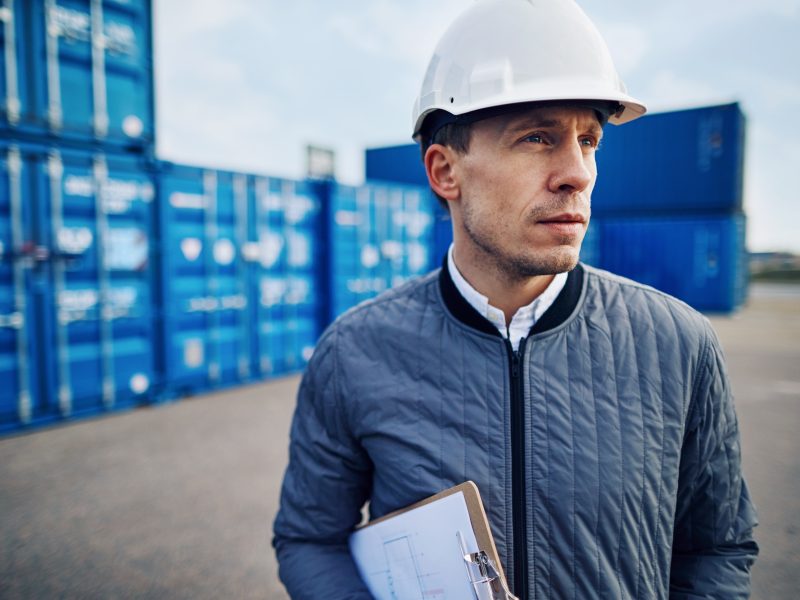 Engineer standing alone on a commercial shipping dock